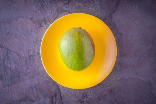 Mango lying on a yellow plate horizontal