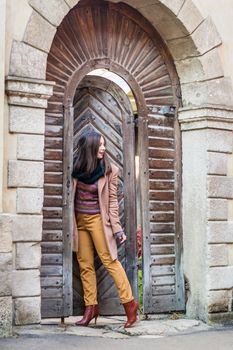 beautiful girl near old wooden gate in the city