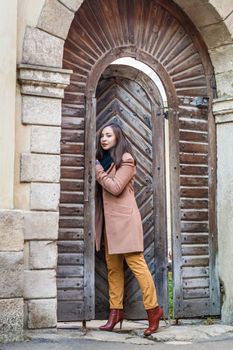 beautiful girl near old wooden gate in the city