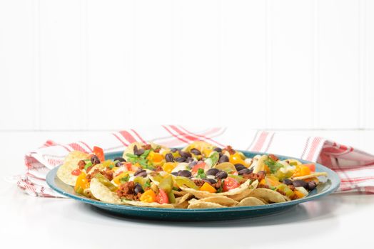 Delicious hot nachos on a green tin platter.