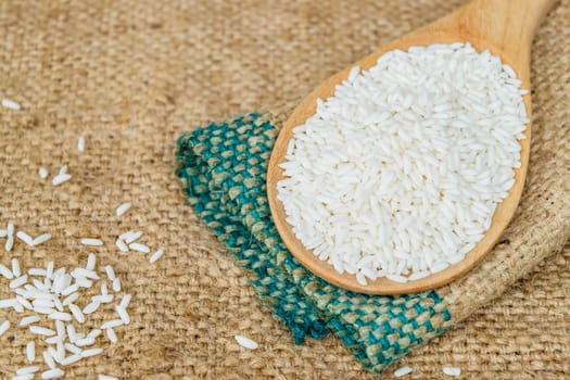 Glutinous rice in wooden spoon with hemp sacks background