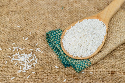 Glutinous rice in wooden spoon with hemp sacks background