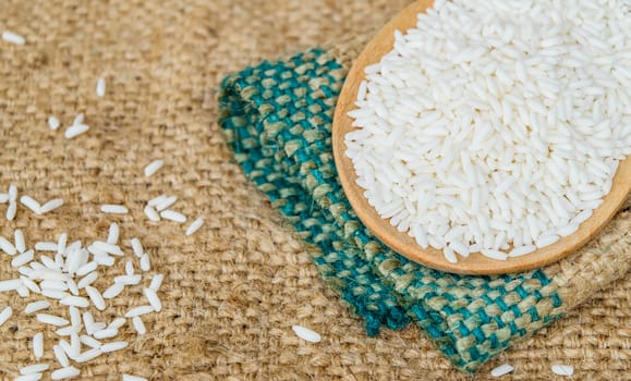 Glutinous rice in wooden spoon with hemp sacks background