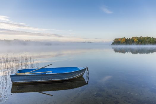 Blue rowboat moored on a misty lake in autumn - Ontario, Canada