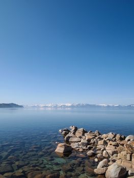 Scenic view of beautiful Lake Tahoe in Spring, landscape of the United States of America, clear water, nice sky, stone island, tree, fresh air and snow mountains