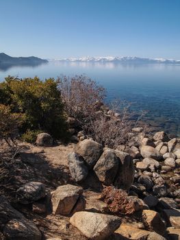 Scenic view of beautiful Lake Tahoe in Spring, landscape of the United States of America, clear water, nice sky, stone island, tree, fresh air and snow mountains