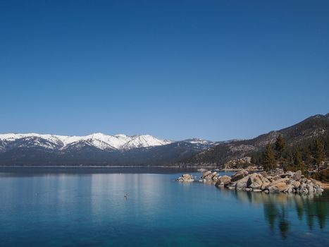 Scenic view of beautiful Lake Tahoe in Spring, landscape of the United States of America, clear water, nice sky, stone island, tree, fresh air and snow mountains