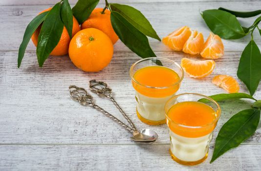 Delicious and rich in vitamins panna cotta with tangarine jam, tangarines and slice of tangarines on a white wooden table