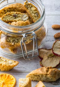 Tasty and healthy almond cookies, rich in vitamins, minerals in a glass jar and almonds and dried apples dried lemons on a white wooden table. Close up
