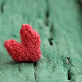 Abstract valentine background with red heart on green wooden in vintage color, knitted heart is symbol for romantic love of couple in feb 14