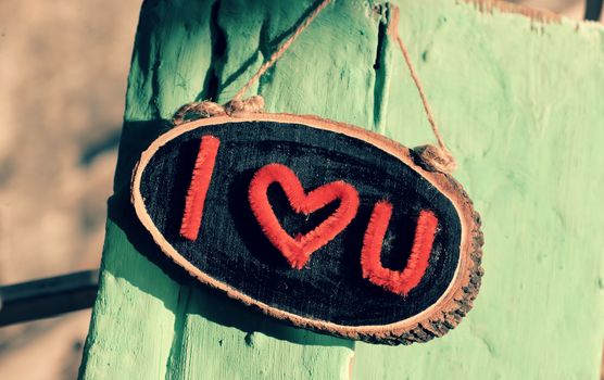 I love you letter in red color on black banner and green wood background, a romantic message for couple in february holiday, shades of sunlight on wood make impression