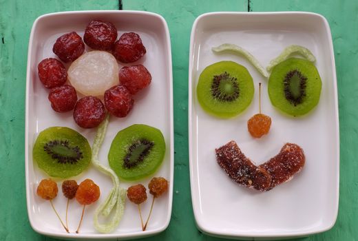 Vietnamese food for Vietnam Tet holiday, also lunar new year of Asia, colorful preserved fruit as kiwi, damson jam, or coconut jam set up on white plate with green wood background make art