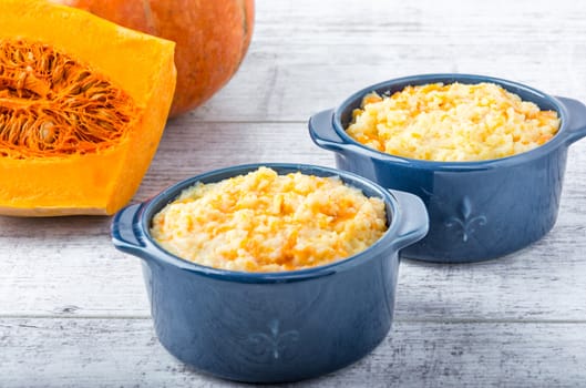 millet porridge with pumpkin in blue bowls and pumpkin  on a white wooden table