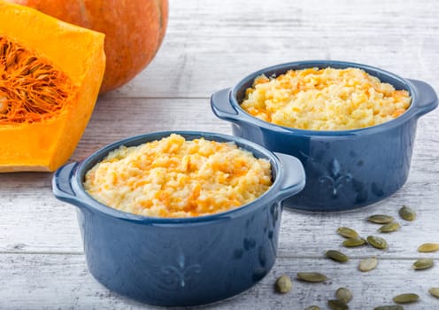 millet porridge with pumpkin in blue bowls, pumpkin and pumpkin seeds on a white wooden table