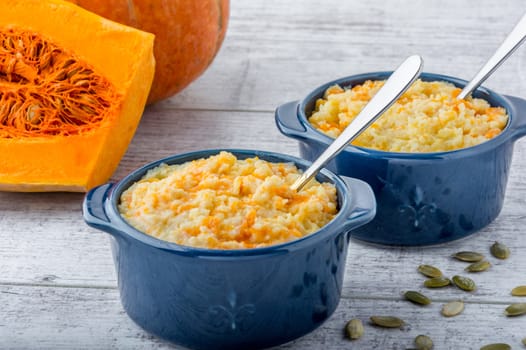 millet porridge with pumpkin in blue bowls, pumpkin and pumpkin seeds on a white wooden table