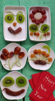 Vietnamese food for Vietnam Tet holiday, also lunar new year of Asia, colorful preserved fruit as kiwi, damson jam, or coconut jam set up on white plate with green wood background make art