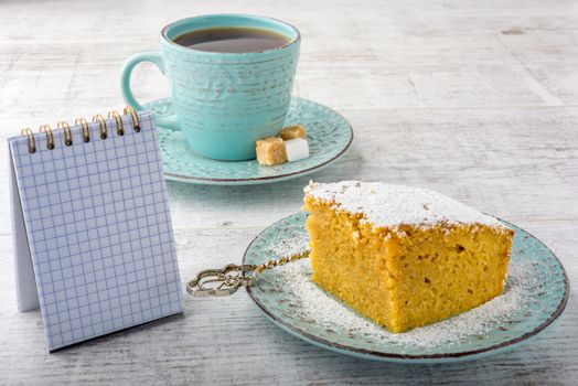 pumpkin pie, tea and note pad on a white wooden table