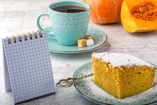 pumpkin pie, tea, pumpkin, pumpkin piece and note pad on a white wooden table