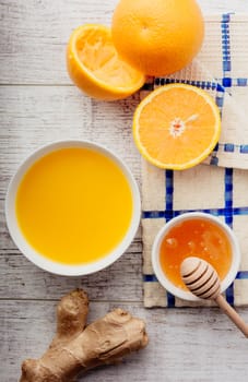 oranges, orange juice with honey and ginger lie on a white wooden table