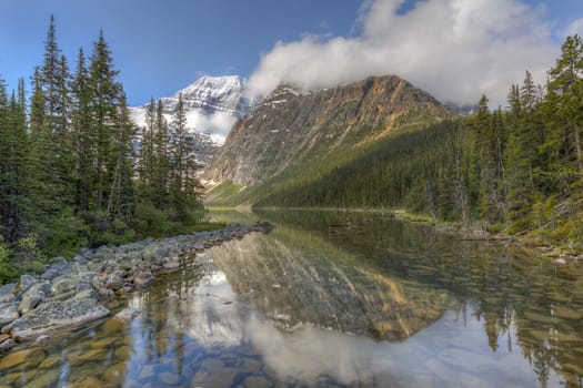 Mountains and the boreal forest reflecting in a lake in early summer - Jasper National Park, Alberta, Canada