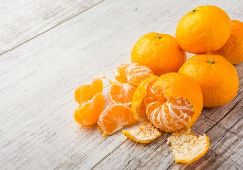 tangerines, peeled tangerine and tangerine slices on a white wooden table