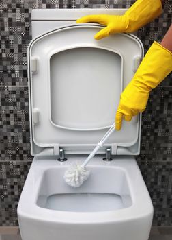 cleaning of toilet bowl in yellow rubber gloves