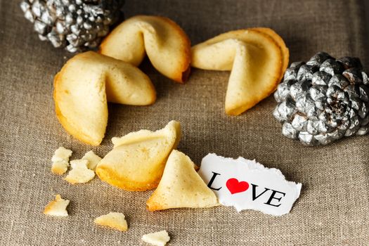 Cookies shaped like tortellini with the word love written on a paper and two silver pineapples in the background.Horizontal image.