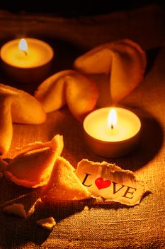 Cookies shaped like a tortellini with the word love written on a paper and two candles lit.Vertical image.