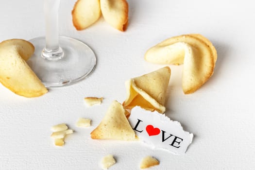 Cookies shaped like tortellini with the word love written on a paper and a glass of champagne.Horizontal image.