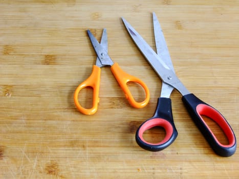Two different Size Scissors on wooden Cutting Board