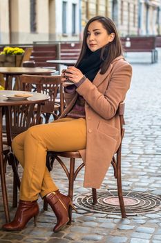 beautiful girl drinking coffee in a cafe on the street