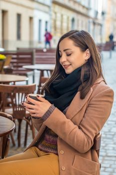 beautiful girl drinking coffee in a cafe on the street