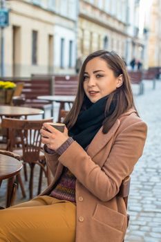 beautiful girl drinking coffee in a cafe on the street