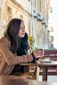 beautiful girl drinking coffee in a cafe on the street