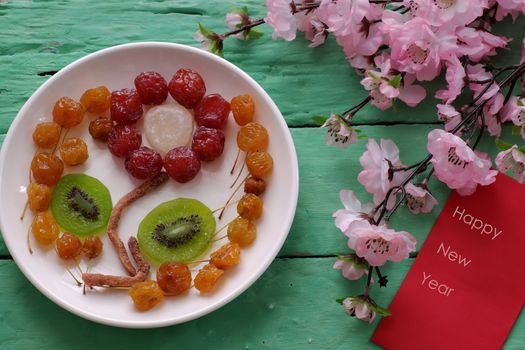 Group of colorful Vietnamese jam for Vietnam Tet holiday on green background, also lunar new year of Asia, traditional preserved fruit from kiwi, damson or coconut jam