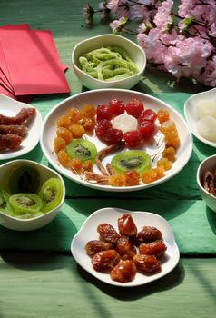 Group of colorful Vietnamese jam for Vietnam Tet holiday on green background, also lunar new year of Asia, traditional preserved fruit from kiwi, damson or coconut jam