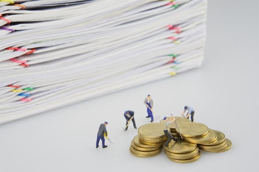 Pile overload document and gold coins with miniature people on white background.