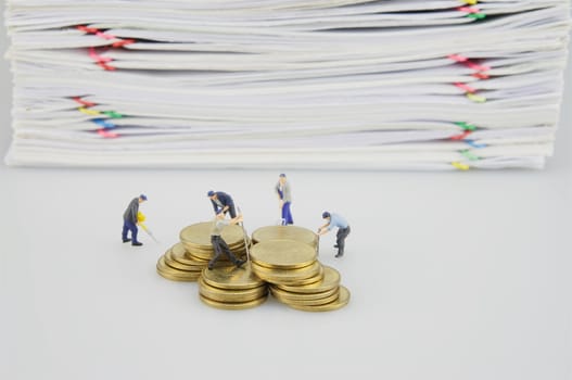 Pile overload document and gold coins with miniature people on white background.