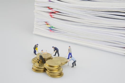 Pile overload document and gold coins with miniature people on white background.