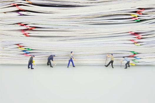 Pile overload paper with colorful paperclip and miniature people are destroyed it on white background.