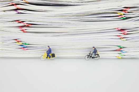 Pile overload paper with colorful paperclip and miniature people are bicycling on white background.