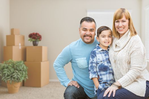 Happy Mixed Race Family with Son in Room with Packed Moving Boxes.