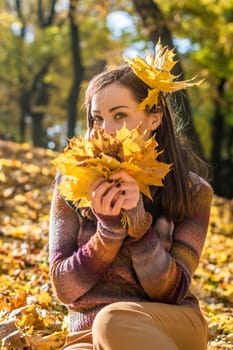 beautiful girl in autumn Park keeps yellow leaves