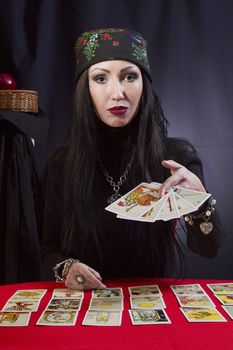 Gypsy woman wonders on the Tarot cards on a black background