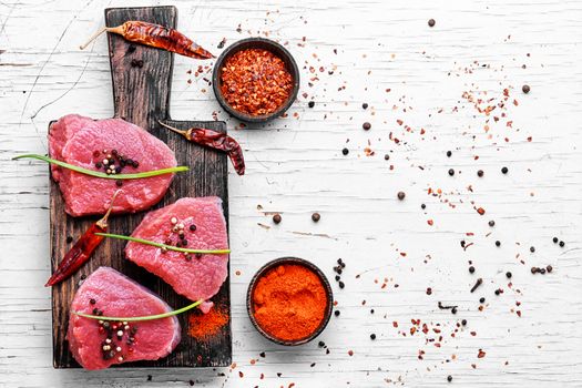 Three raw chops veal steak with peppers and spices