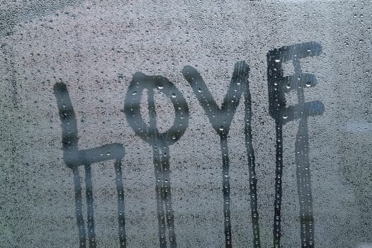 Macro texture water drops on clear glass surface with Love written text