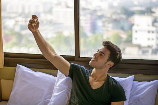 Handsome smiling man doing selfie with smartphone. Horizontal indoors shot