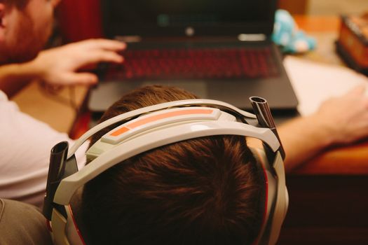 Boy wearing headphones playing online games on a laptop.