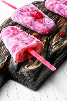 three pomegranate ice creams on sticks on the kitchen board