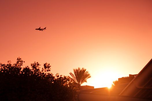 plane silhouette on the horizon against the setting sun.